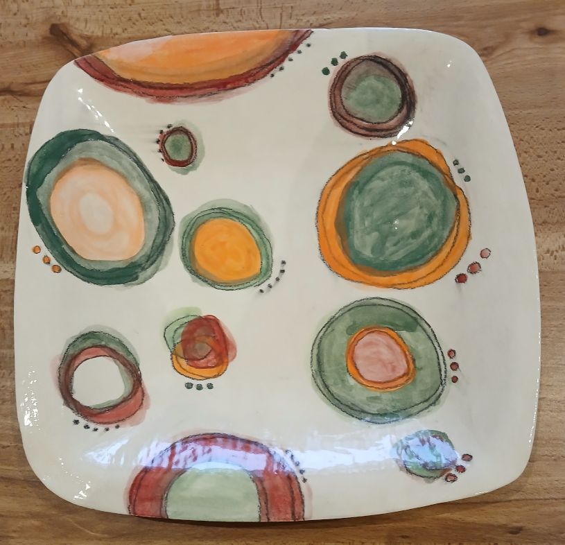 Squarish shaped plate decorated with colourful circles.